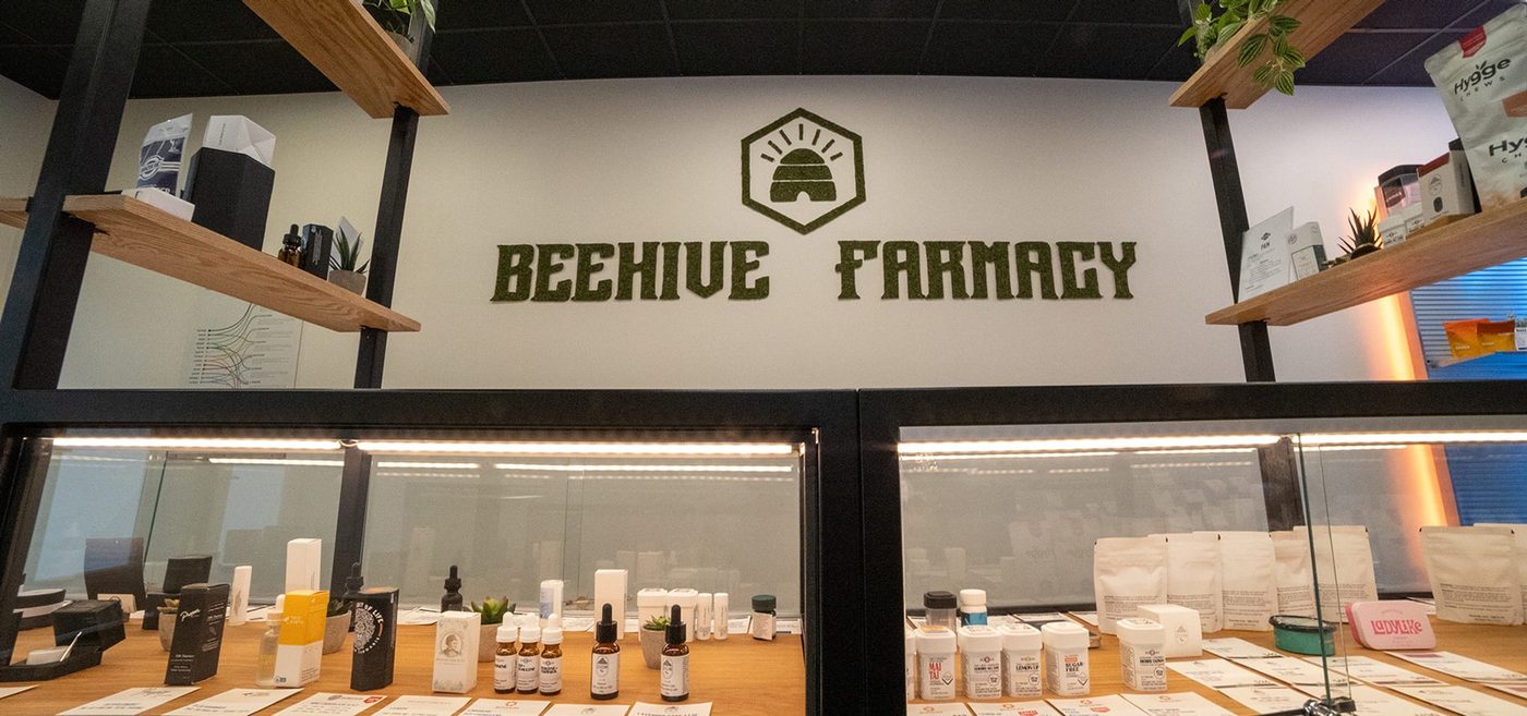 Beehive Farmacy logo on wall above display cases of cannabis products